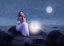 Dziewczyna na skale obok świecącej latarenki