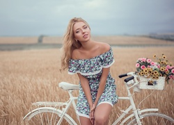 Dziewczyna oparta o rower z widokiem na łany zbóż