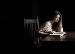 Dziewczyna siedząca z książką przy stole