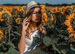 Dziewczyna w kapeluszu pomiędzy słonecznikami