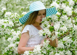 Dziewczyna w kapeluszu pośród kwitnących wiosennych gałązek