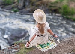 Dziewczyna w kapeluszu siedząca na skale