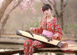 Dziewczyna w kimonie gra na koto - tradycyjnym japońskim instrumencie
