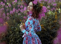 Dziewczyna w kwiecistej sukience i wianku na łące pełnej kwiatów