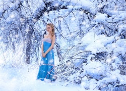 Dziewczyna w letniej sukience w zimowym lesie