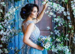 Dziewczyna w niebieskiej sukience z bukietem kwiatów w dłoni