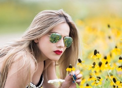 Dziewczyna w okularach przeciwsłonecznych pośród kwiatów