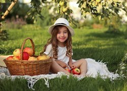 Dziewczynka na kocu z koszem jabłek