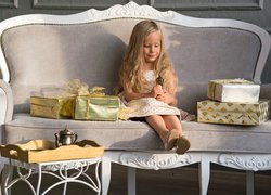 Dziewczynka na sofie ogląda prezenty