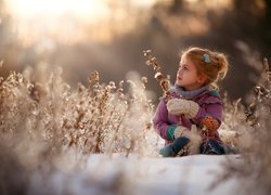 Dziewczynka pośród roślinek w zimowej scenerii