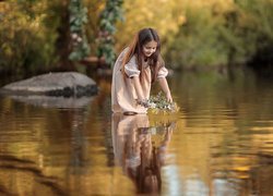 Dziewczynka puszczająca wianek na rzece