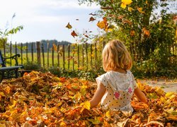 Dziewczynka siedząca w jesiennych liścich