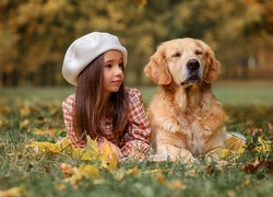 Dziewczynka w białym berecie i golden retriever na łące