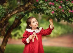 Dziewczynka w czerwonej sukience pod kwitnącym drzewem