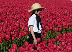 Dziewczynka w kapeluszu wśród tulipanów