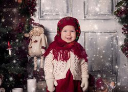 Dziewczynka w kolorowej chuście przy świątecznej choince
