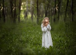 Dziewczynka wśród konwalii w lesie