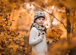 Dziewczynka z bukietem jesiennych liści w dłoni