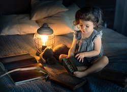 Dziewczynka z książkami i pluszakiem obok lampy