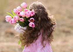Dziewczynka z naręczem różowych tulipanów