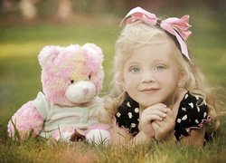 Dziewczynka z różowym misiem w trawie