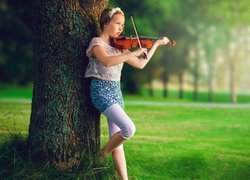 Dziewczynka ze skrzypcami oparta o drzewo