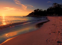 Fale na morskiej plaży o zachodzie słońca