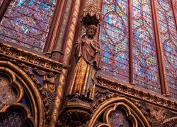 Figura na tle witraży w kaplicy Sainte Chapelle w Paryżu