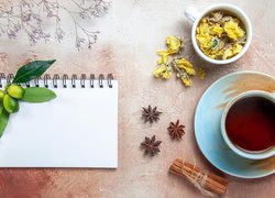 Filiżanka herbaty obok notesu i suchych płatków kwiatów