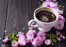 Filiżanka kawy i różowe kwiaty na desce