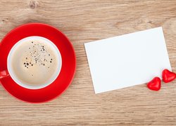 Filiżanka kawy obok białej kartki i serduszek