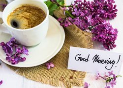 Filiżanka kawy obok bzu i napisu Good Morning na karteczce