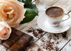 Filiżanka kawy obok róż i czekolady