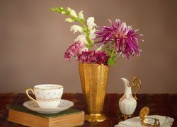 Filiżanka kawy obok wazonu z kwiatami i zegarka na serwetce