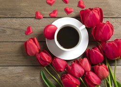 Filiżanka kawy pośród czerwonych tulipanów