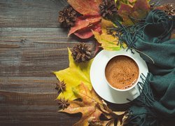 Filiżanka z kawą na jesiennych liściach obok szala