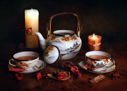 Filiżanki z herbatą obok świec i czajniczka