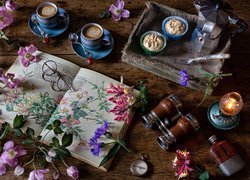 Filiżanki z kawą i babeczki obok kwiatów na książce i lampy