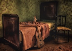 Gitara oparta o łóżko i krzesło w starym pokoju