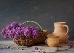 Gliniane naczynia obok kosza z kwiatami bzu