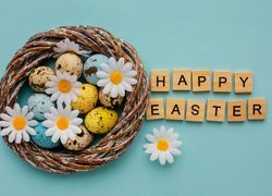 Gniazdo z pisankami i stokrotkami obok napisu Happy Easter