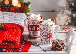 Gorąca czekolada z piankami w kubku obok świątecznego swetra