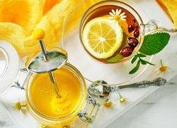 Herbata z cytryną obok słoika miodu
