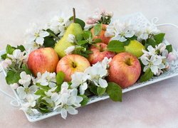 Jabłka i gruszki pośród białych kwiatków na tacy