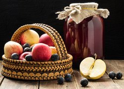 Jabłka i jagody w koszyku obok słoja