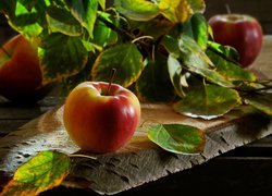 Jabłka i liście na desce