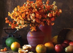 Jabłka i pomarańcze obok wazonu z kwiatami