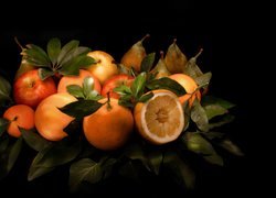 Jabłka, pomarańcze i gruszki ułożone między liśćmi