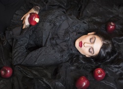 Jabłka ułożone obok dziewczyny w czarnej sukience