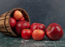 Jabłka wysypane z drewnianego wiaderka